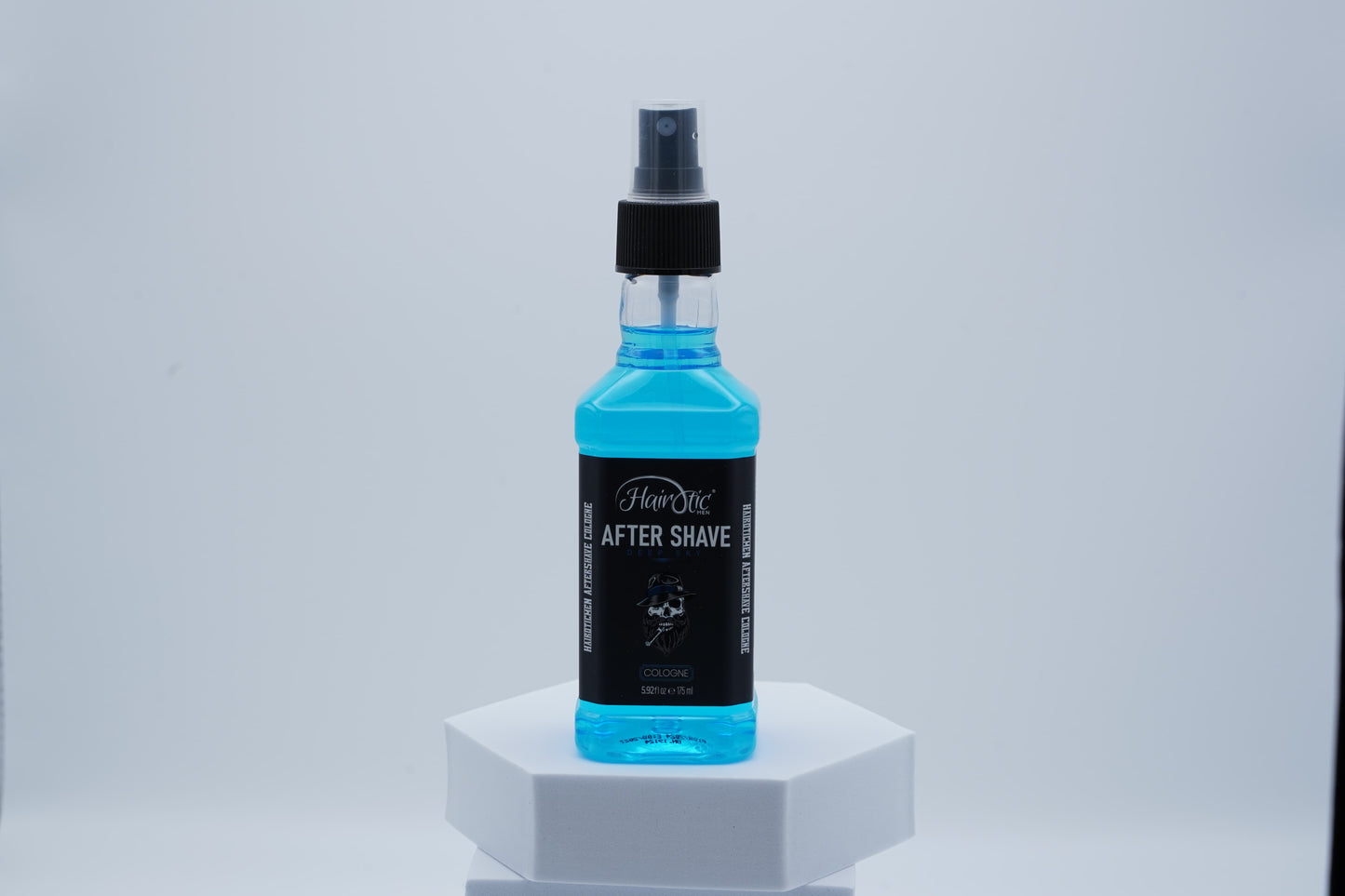 Blaue Sprühflasche Hairotic After Shave Deep Sky, stehend auf weißem Podest vor neutralem Hintergrund.
