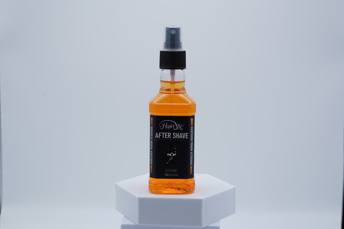 Orangefarbene Sprühflasche Hairotic After Shave Golden Sands, platziert auf weißem Podest vor neutralem Hintergrund.