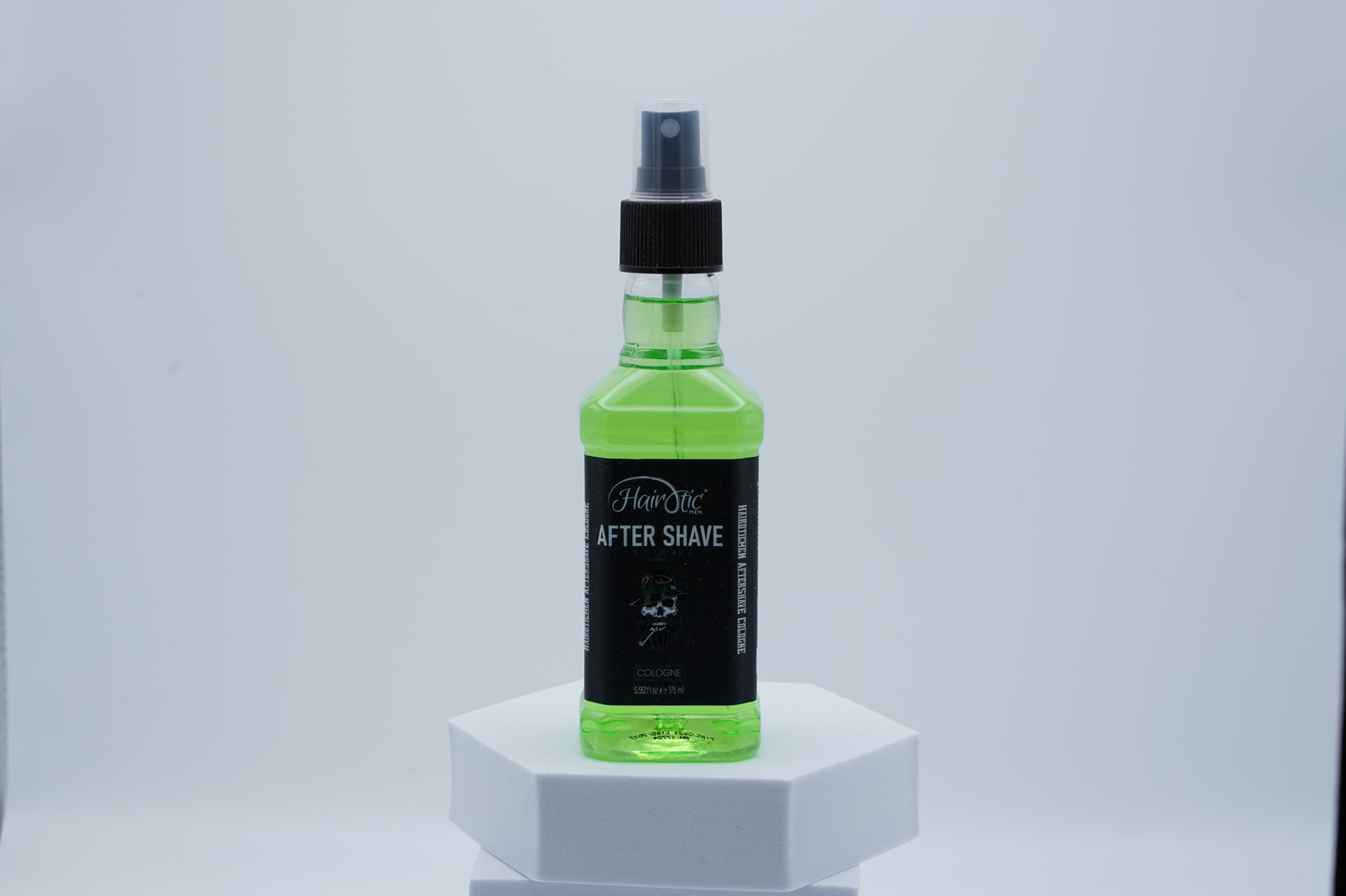 Grüne Sprühflasche Hairotic After Shave Infinite, stehend auf weißem Podest vor neutralem Hintergrund.