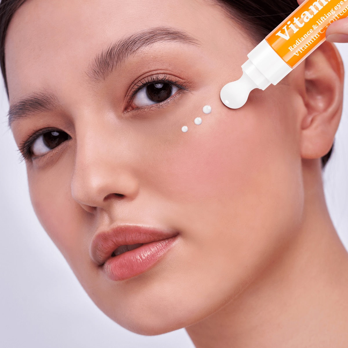 Frau trägt eine Augencreme mit Vitamin C aus einem Tubenapplikator punktuell unter dem Auge auf, Nahaufnahme der Gesichtspartie mit Fokus auf strahlende Hautpflege.