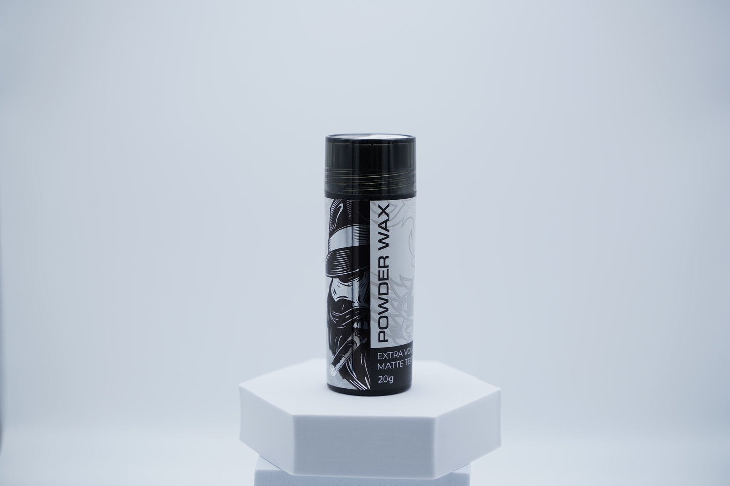 Schwarze Dose Hairotic Powder Wax mit weiß-schwarzem Etikett für extra Volumen und mattes Finish, 20 g, auf weißem Podest vor hellem Hintergrund.