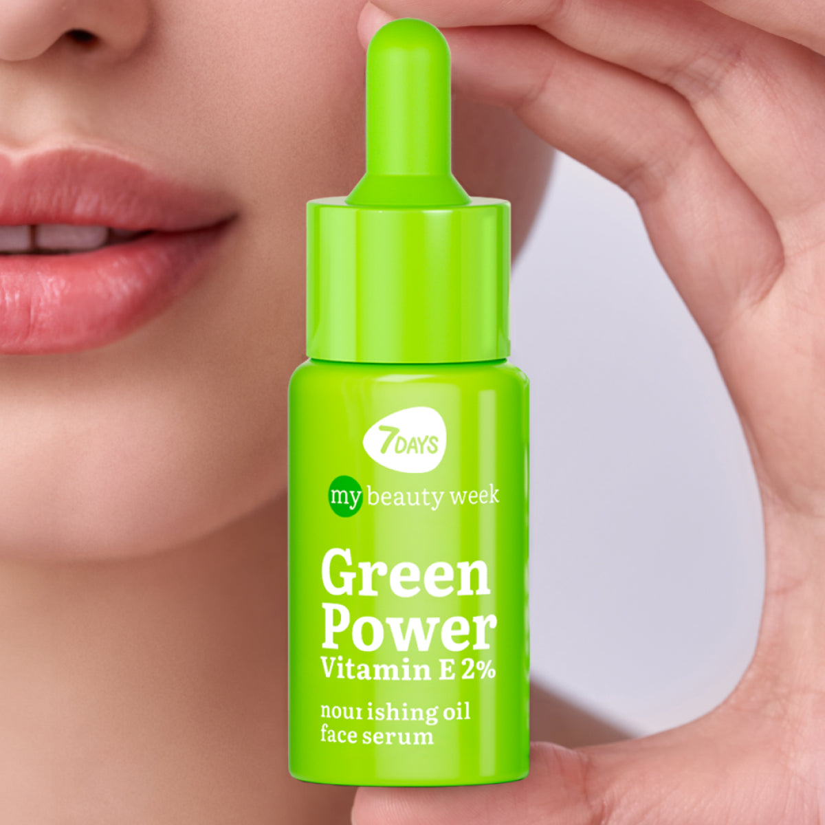 Nahaufnahme eines Gesichts mit natürlichem Teint, in der Hand ein grünes Fläschchen des 7DAYS My Beauty Week Green Power Face Serum mit Vitamin E 2 % gehalten.