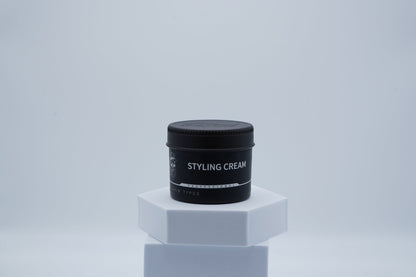 Schwarze Dose Hairotic Styling Cream für alle Haartypen auf weißem Podest, minimalistischer Hintergrund.