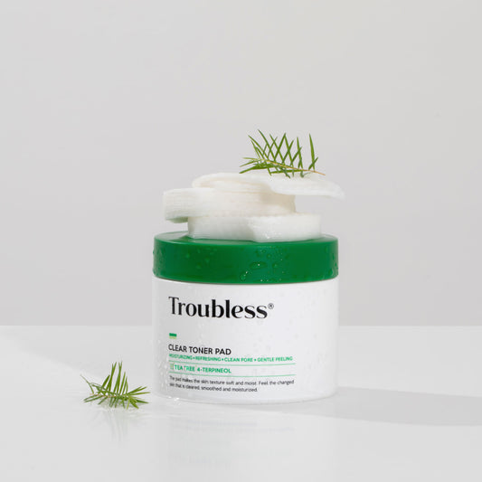 Troubless Clear Toner Pad – runde Dose mit grünem Deckel, Pads gestapelt, dekoriert mit Teebaumzweig