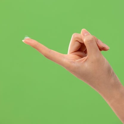 Troubless Invisible Spot Patch – durchsichtiges Pickelpatch auf Fingerspitze vor grünem Hintergrund